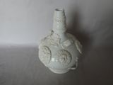 a white vase sitting on a table with a white wall in the background