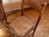 a wooden chair with a woven seat next to a dresser