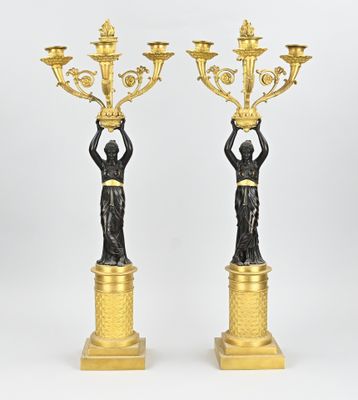 une paire de figurines en bronze représentant une femme tenant un candélabre