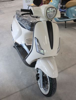 un scooter blanc garé dans un garage, avec d'autres scooters en arrière-plan