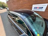 une voiture garée devant un immeuble sur le mur latéral duquel est accrochée une pancarte