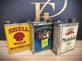 three vintage shell oil cans are lined up on a wooden table