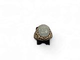 a close up of a ring with a stone in it on a white surface
