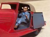 une petite voiture avec un homme en costume assis au volant