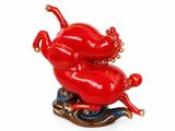 a figurine of a red pig riding a wave