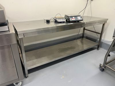 une table de travail en acier inoxydable sur laquelle sont posés deux téléphones, dans une cuisine