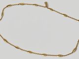 a close up of a gold necklace on a white surface
