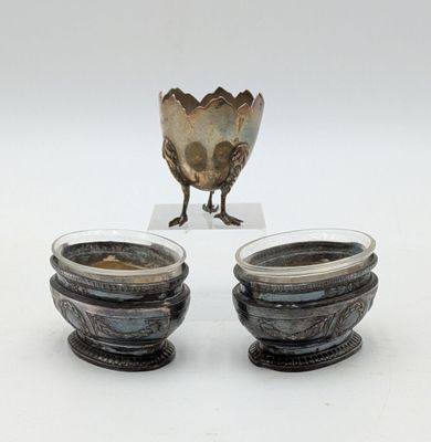 two silver bowls sitting next to each other on a white surface