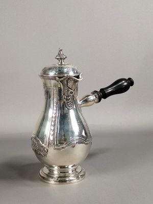 a silver coffee pot with a black handle on a table
