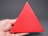 someone is holding a red triangular shaped object in their hand