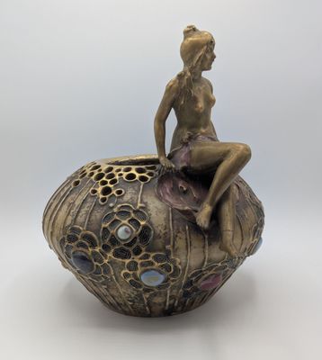 statue d'une femme assise au sommet d'un objet décoratif