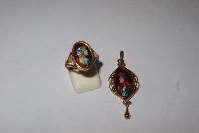 a close up of two rings and a pendant on a white surface