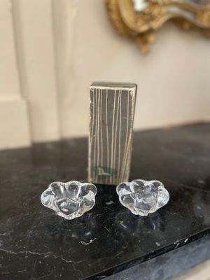une paire de bougeoirs en verre transparent posés sur une table en marbre noir