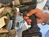 a person holding a cordless drill with a cat in the background