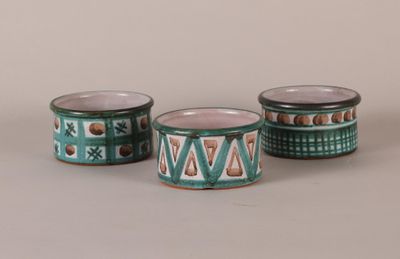 three green and white cups with designs on them on a gray surface