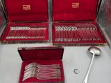 Plusieurs pièces d'argenterie se trouvent dans un coffret rouge posé sur une table