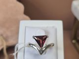 une bague sertie d'une pierre rouge, présentée dans un coffret blanc