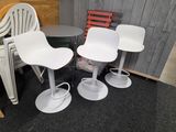 trois chaises blanches et une table dans une pièce