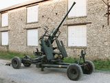 a large machine gun sitting on a cart in front of a building