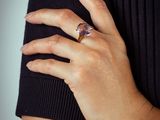 someone is wearing a ring with a pink stone on it