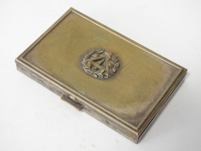 un étui à cigarettes ancien en laiton, orné d'un blason sur le devant