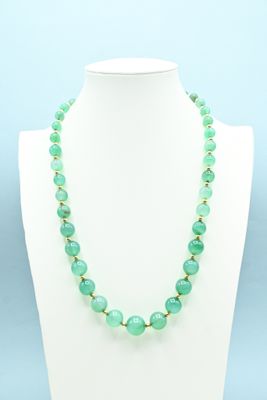 a green beaded necklace on a white mannequin