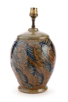 un vase brun et bleu posé sur une surface blanche