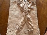 une figurine en papier mâché représentant un homme assis sur une table, tenant une paire de ciseaux