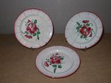 trois assiettes ornées de roses, posées sur une table