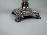 a silver candle holder on a stand on a white surface