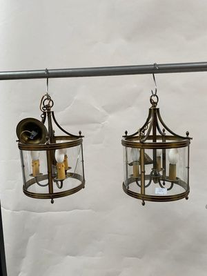 two lanterns hanging from a metal pole on a white wall