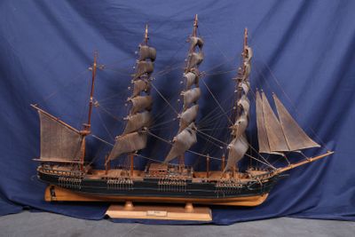 une maquette en bois d'un navire exposée sur un fond bleu