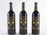 three bottles of wine are lined up on a white surface