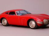a red toy car that is sitting on a gray surface