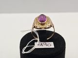 une image représentant une bague ornée d'une pierre violette posée sur un support noir