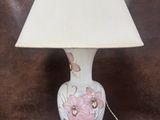 une lampe posée sur une table, avec un abat-jour blanc