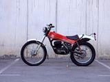 a red motorcycle parked in a parking lot next to a white wall