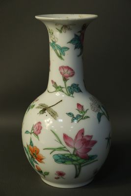 a white vase with pink flowers and a dragonfly on it