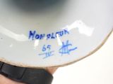 a person holding a white vase with blue writing on it