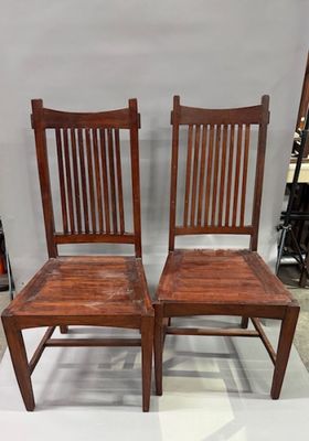 Il s'agit de deux chaises en bois placées l'une à côté de l'autre sur un sol blanc.