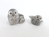 une paire de figurines de chouettes en argent sur fond blanc