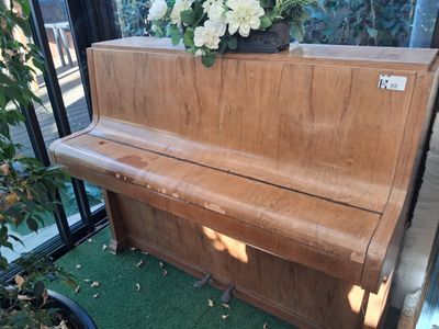 a wooden piano with a plant on top of it