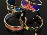 three different colored bracelets on a black surface with reflection