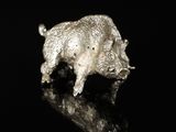 a silver figurine of a boar on a black surface