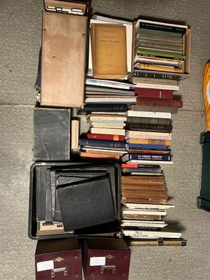une pile de livres posée par terre, à côté d'une valise et d'un réveil