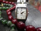 a close up of a watch on a table with a bunch of beads