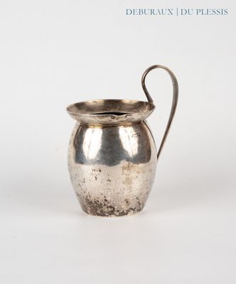 a silver pitcher with a handle on a white surface