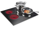 trois casseroles et poêles posées sur une plaque de cuisson
