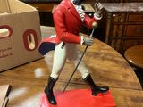 une figurine représentant un homme vêtu d'une veste rouge et d'un chapeau, posée sur une table