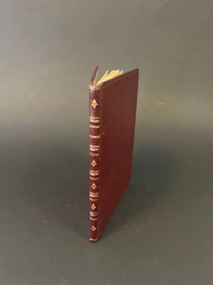 a red book with gold trim sitting on top of a table